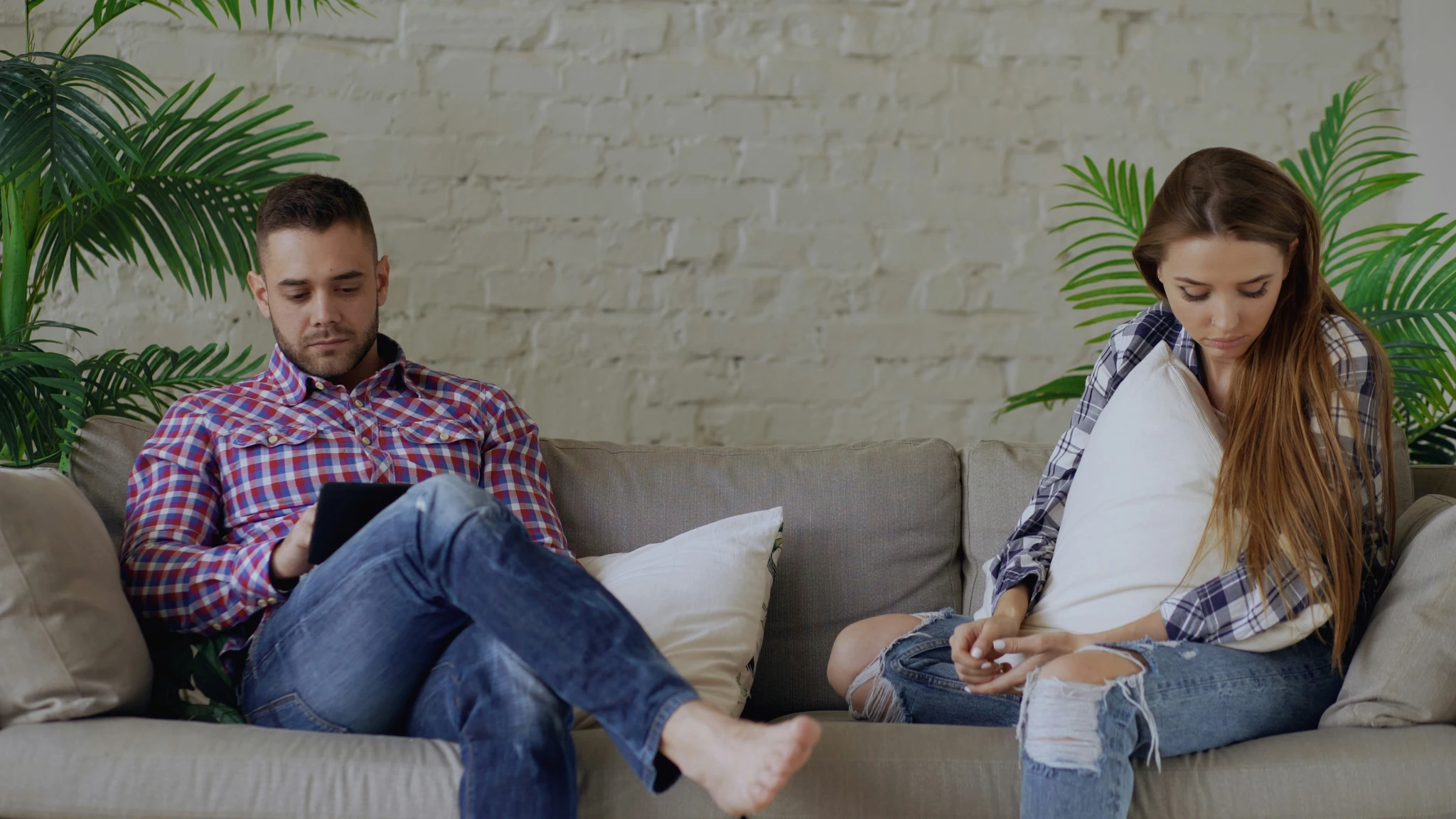 Couple feeling disconnected from each other while sitting apart on a couch