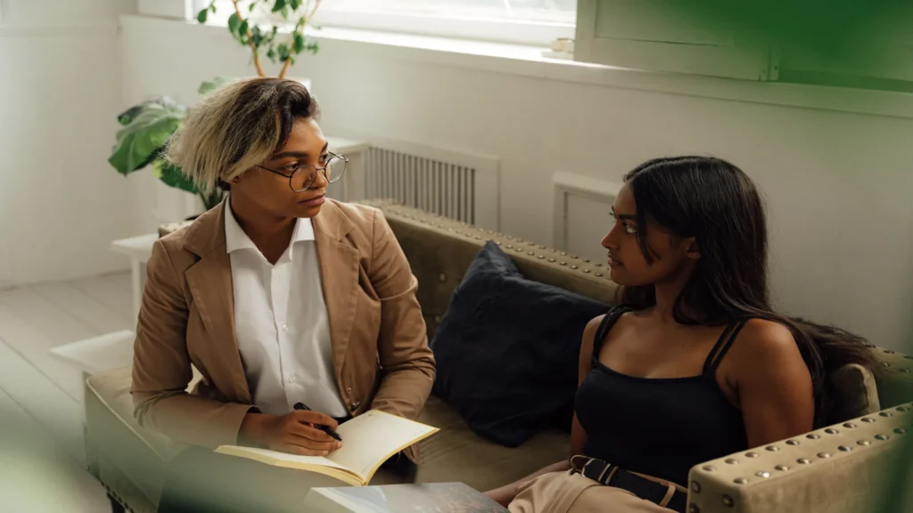 Therapist taking notes while listening to a client during a counseling session