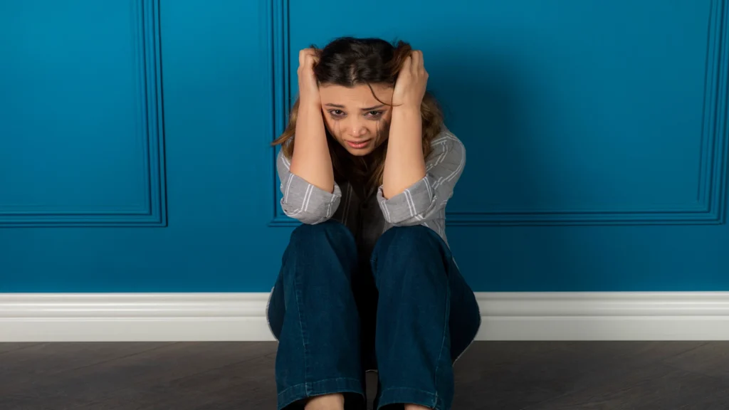 Woman sitting on the floor feeling overwhelmed during a panic attack